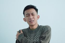 Asian young man touching shoulder in pain