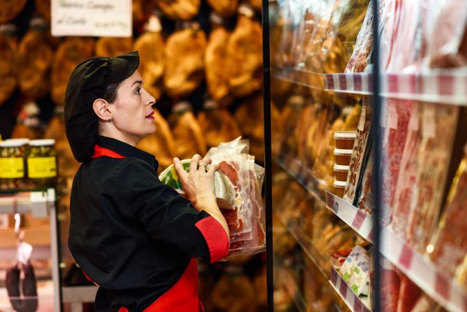 Woman in butcher shop arranging meat on shelf