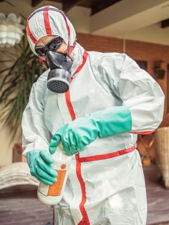 Man in suit for fumigation pouring chemical into tank