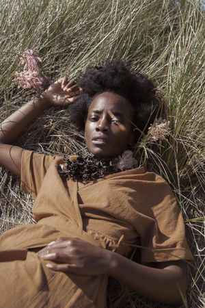 Black woman in brown laying on brown grass