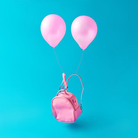 Pastel pink bag with balloons floating on blue background