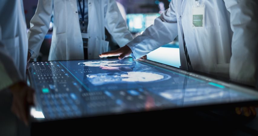 Hospital Medical Research Center: Focus On Hand Gestures Of Diverse Colleagues Gathered Around Interactive Touch Screen Table With MRI Scans Of Brain On Display.