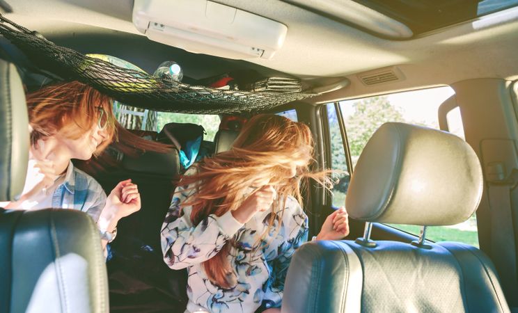 Happy women dancing and having fun inside of car