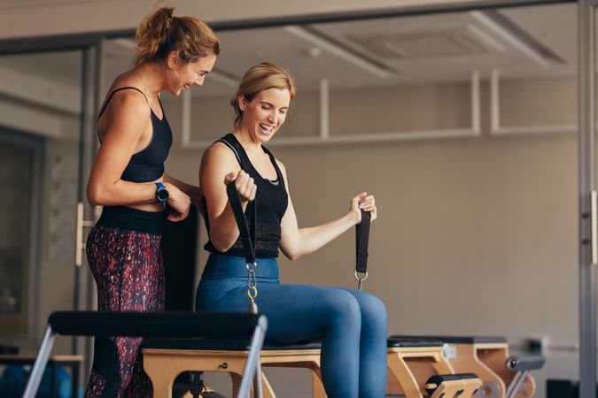 Smiling woman at the gym doing pilates training with her trainer