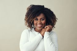 Portrait of beautiful smiling woman with hands clasped against light background