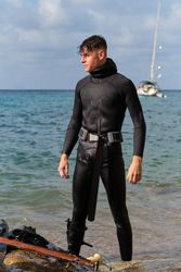 Male hunter in wetsuit preparing for spearfishing on shore
