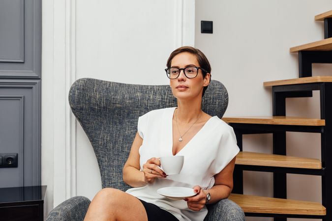 Woman sitting near stairs with a coffee