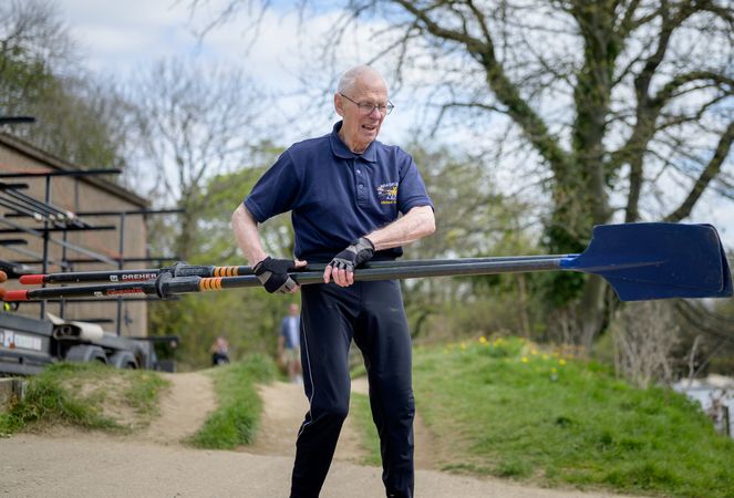 Older man walking with oars