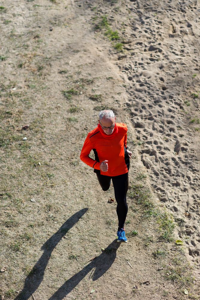 Looking down at older man jogging in park, vertical