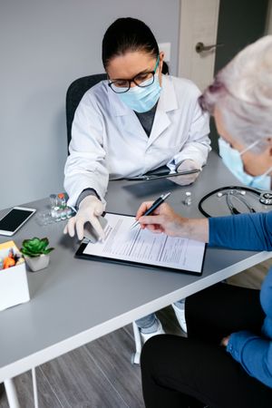 Doctor explaining to her patient consent form to coronavirus vaccine