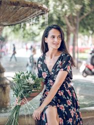 Charming female resting on edge of fountain with bouquet