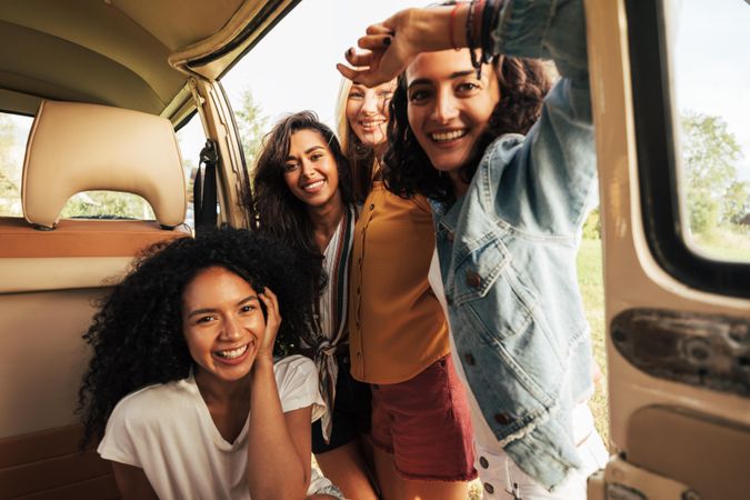 Smiling group of friends posing in an open van door