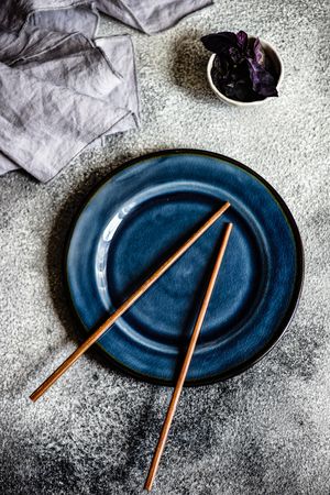 Asian style table setting on navy plate with chopsticks