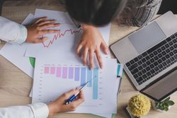 Two people discussing bar charts in an office