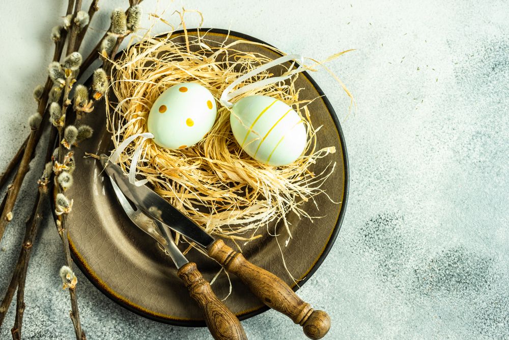 Top view of Easter holiday concept with pastel decorative eggs in nest on plate with pussy willow