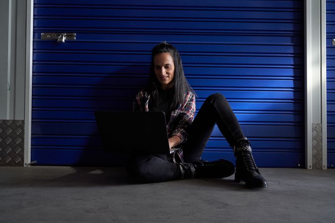 Positive woman browsing laptop near storage