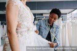 Woman making adjustments to bridal gown in her boutique 4d6YQ0