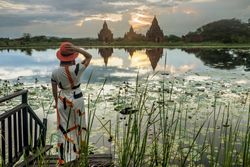 Woman standing at lakeside and enjoying view of Buddhist temples