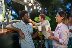 Cheerful multiethnic couple enjoying hot drink in cafe