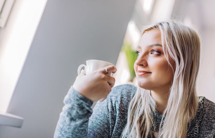 Positive woman holding cup in office