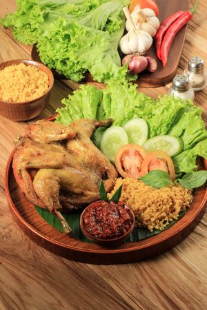 Plate of Indonesian chicken dish served with salad and spicy sauce