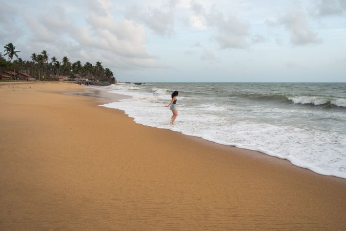 Woman in beachwear walking on sand barefoot