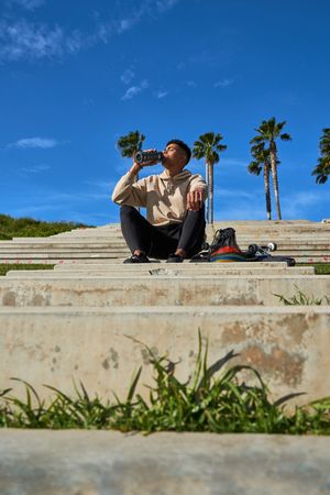 Latino man drinking water from bottle after riding skateboard
