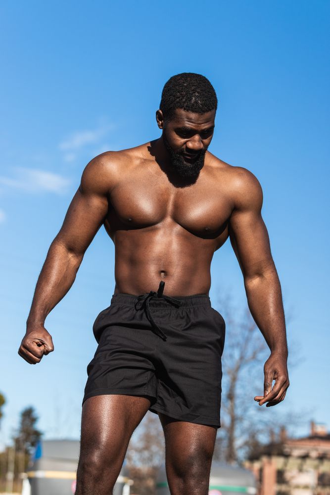 Strong Black sportsman resting during training on sports ground