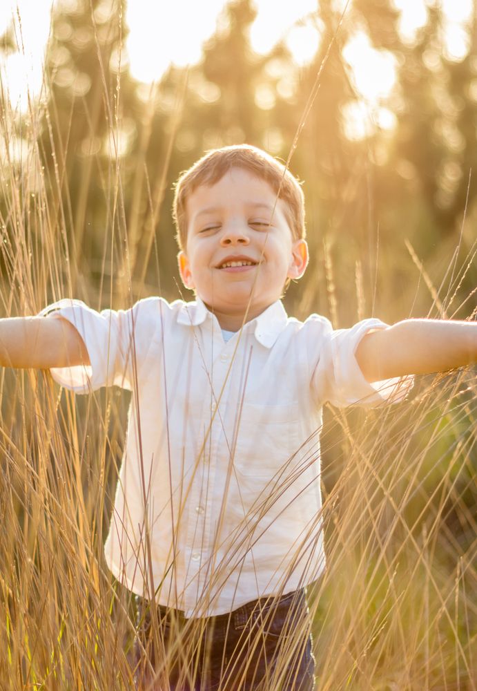Kid in field playing with spikes at summer sunset