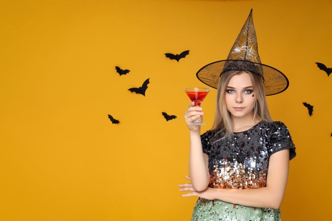 Concept of Halloween, young woman on yellow background