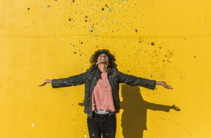 Black woman with afro hair celebrating with confetti.