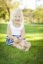 Cute Little Girl Sitting and Laughing in the Grass