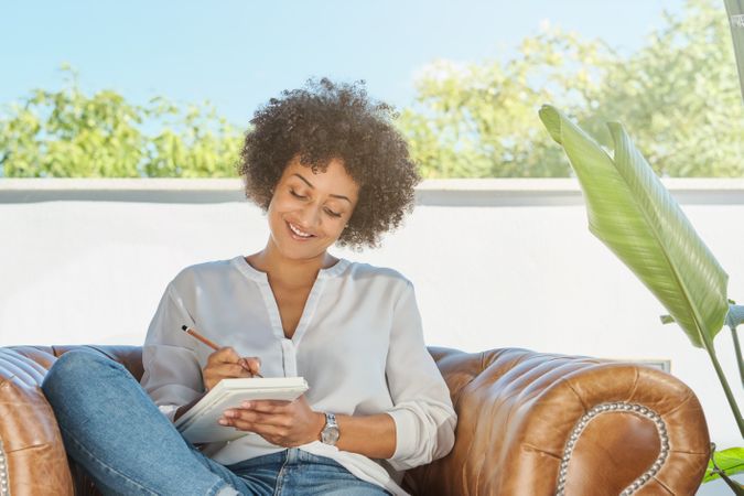 Smiling Hispanic woman taking notes in notepad