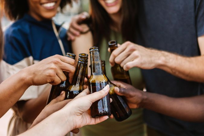 Hands of friends cheering with their beer bottles