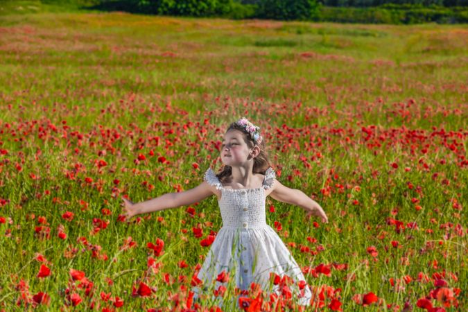 Young girl in light dress standing in red flower field