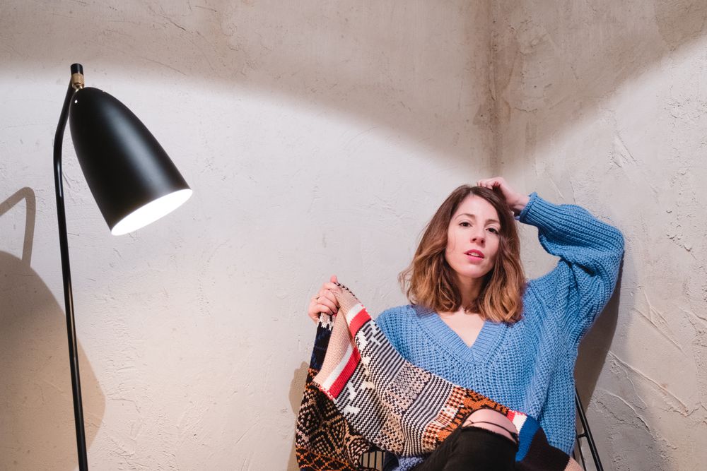 Woman in sweater sitting near wall