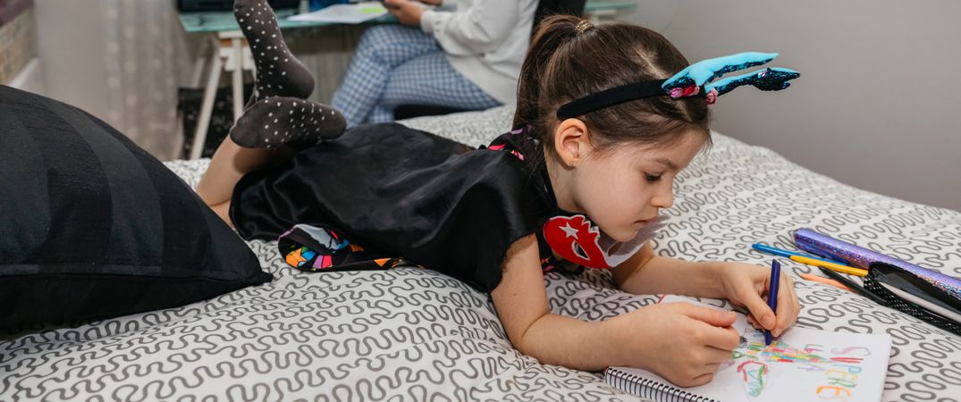 Girl drawing in disguise while her mother teleworking