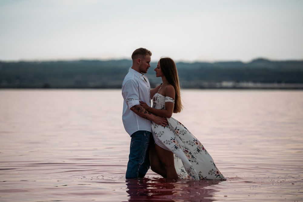 Side view of adorable couple embracing into an amazing beach with pink water