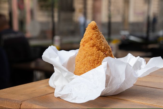 Traditional sicilian rice arancini street food served paper wrapper wooden table authentic italian cuisine snack takeaway quick meal