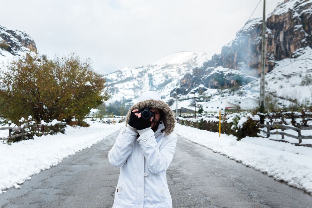 Content woman taking picture in snowy mountains