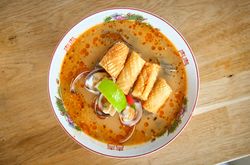 Appetizing soup with noodles and seafood on table