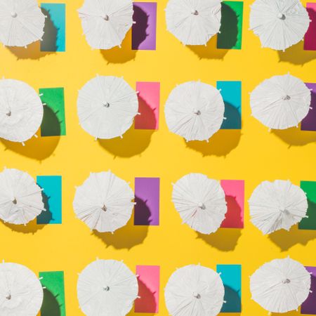 Pattern of sun umbrellas and multicolored towels in rows on yellow