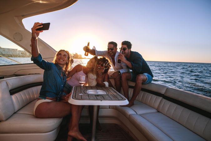 Young woman taking selfie with friends behind her on boat