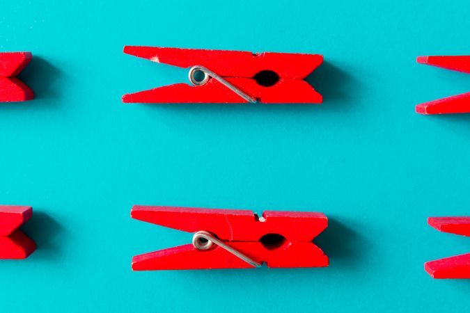 Red clothespins on cyan background
