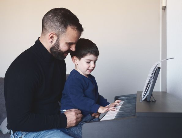 Father teaching son to play piano
