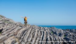 Woman with outstretched arms on rocks near the coast bejPP0