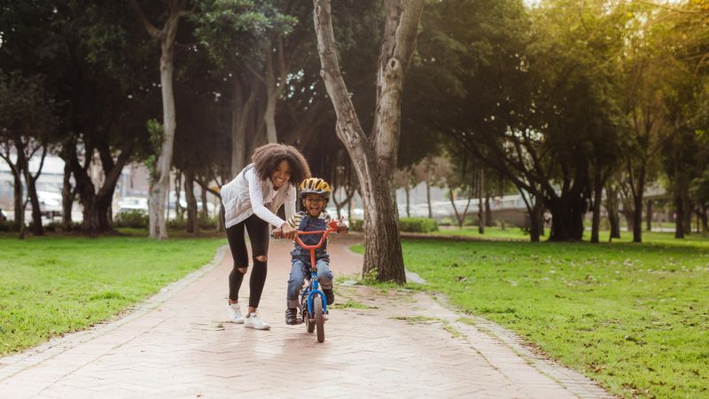 Little preschool boy and his mother in park with a bicycle