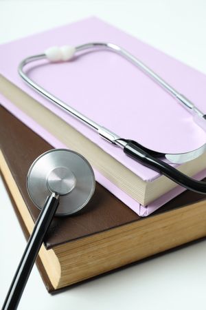 Books and stethoscope on light background, close up