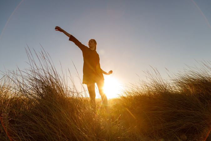Woman posing between field at sunset
