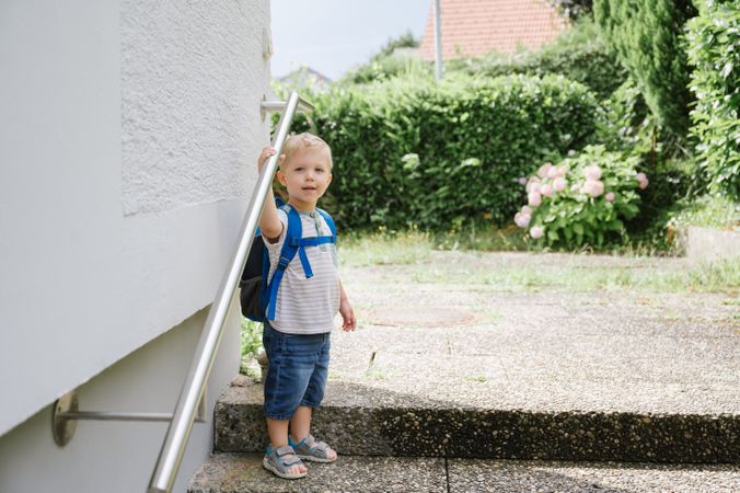 Happy child with backpack standing outside